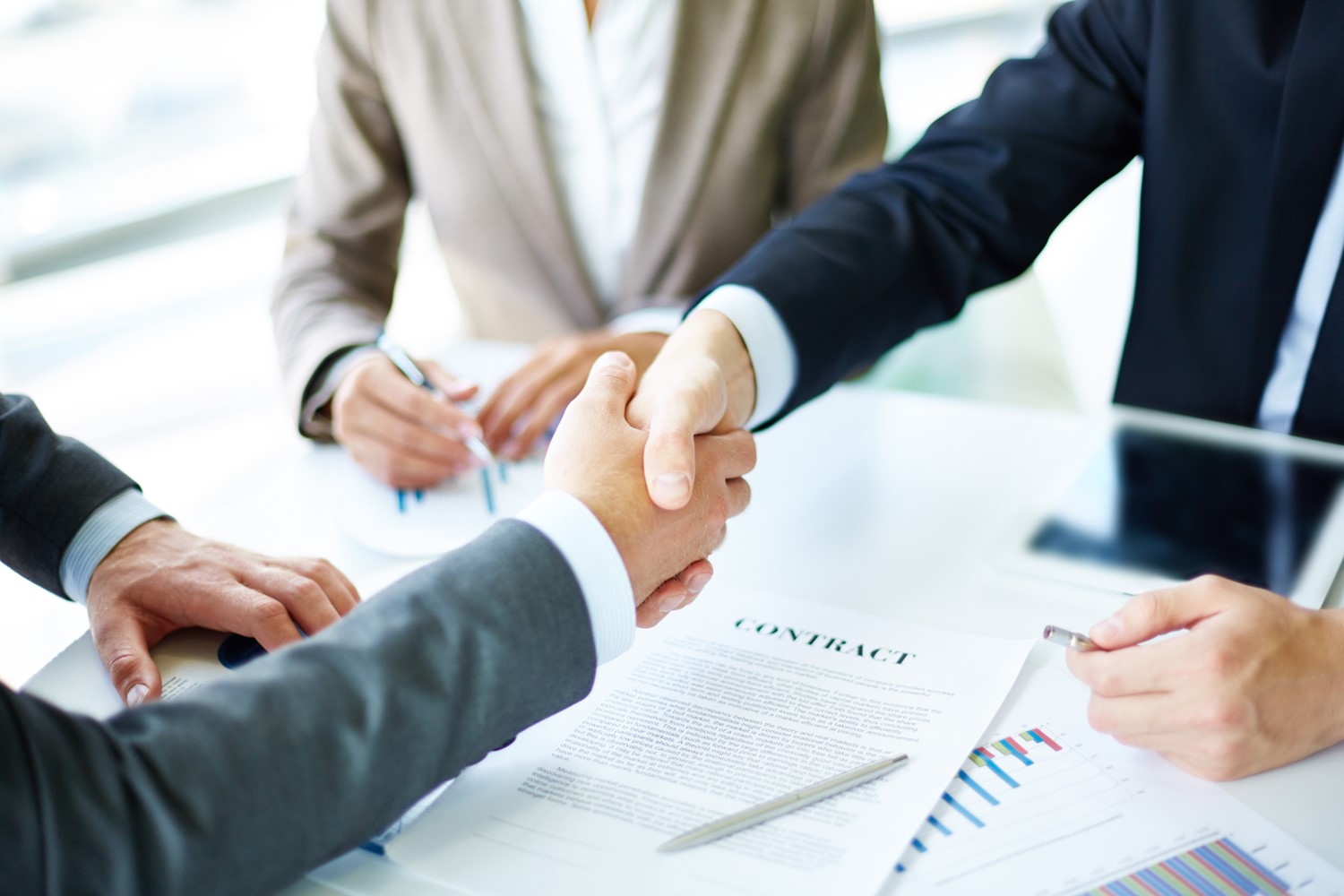 White collar mixed workers of a Foreign direct invested company and EOR services provider shake hands and sign an EOR service agreement