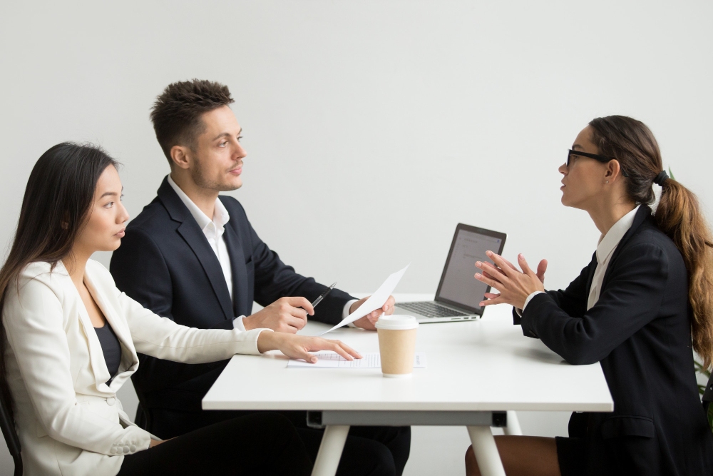 female applicant interviewed by hr manager and recruiter with tough questions face to face office setting 