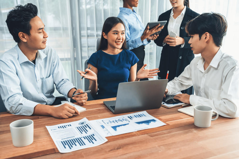 A female consultant for a RPO service in Vietnam is having a discussion with clients about project performance and timeline in office setting